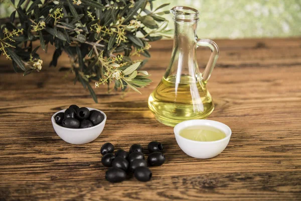 Aceite de oliva y olivo y aceitunas negras y botellas con aceituna — Foto de Stock
