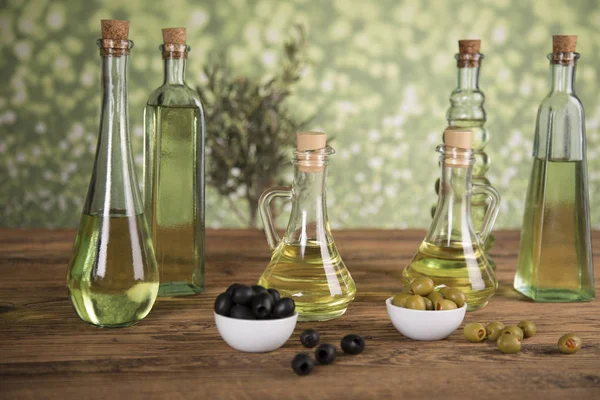 Оливковое масло, оливковое дерево и зеленые и черные оливки на деревянной вкладке — стоковое фото