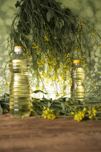 Fleurs de colza et huile de colza dans une bouteille sur la table — Photo