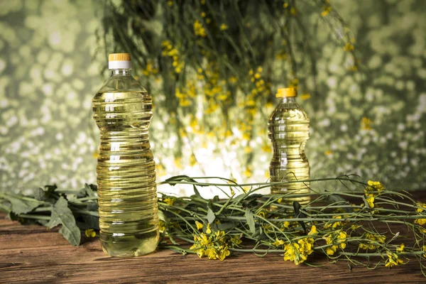 Rapeseed flowers and rapeseed oil in a bottle on the table — Stock Photo, Image