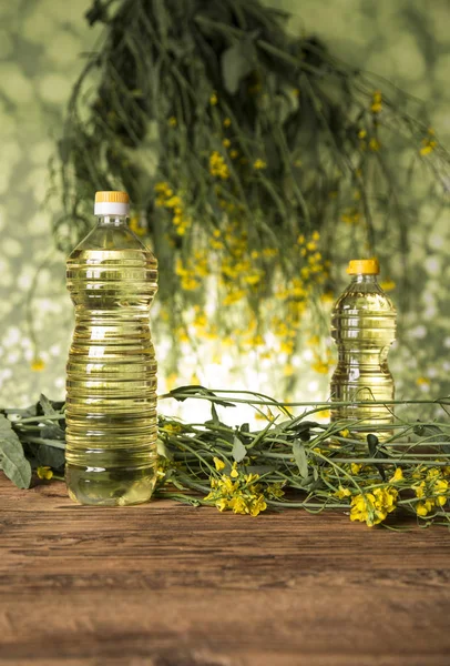 Rapeseed flowers and rapeseed oil in a bottle on the table