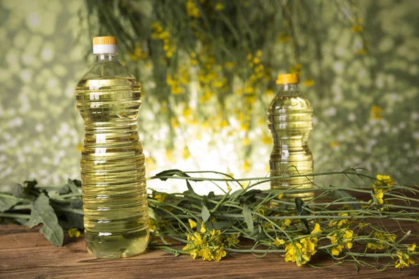 Квіти ріпаку та олія ріпаку в пляшці на столі — стокове фото