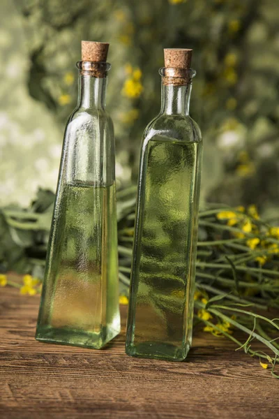 Rapeseed flowers and rapeseed oil in a bottle on the table — Stock Photo, Image