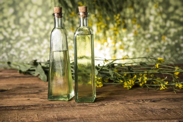 Koolzaadbloemen en raapzaadolie in een fles op tafel — Stockfoto