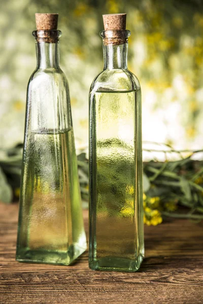 Rapeseed flowers and rapeseed oil in a bottle on the table