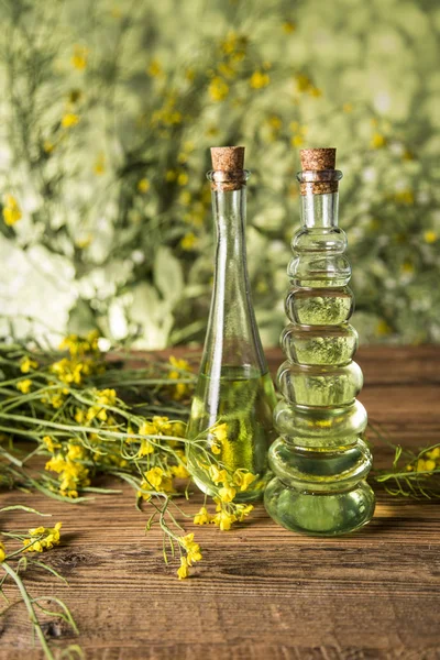 Fleurs de colza et huile de colza dans une bouteille sur la table — Photo