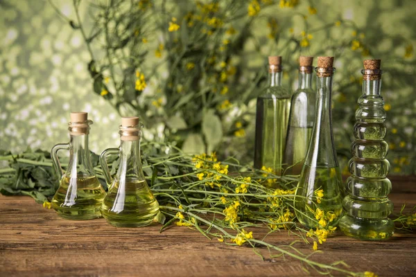 Fiori di colza e olio di colza in una bottiglia sul tavolo — Foto Stock