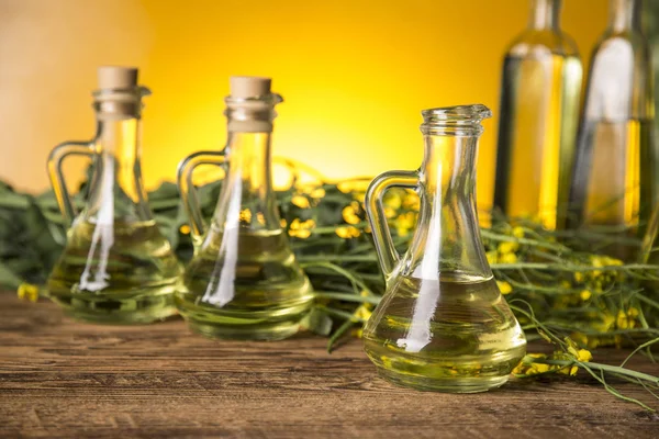 Rapeseed flowers and rapeseed oil in a bottle on the table — Stock Photo, Image