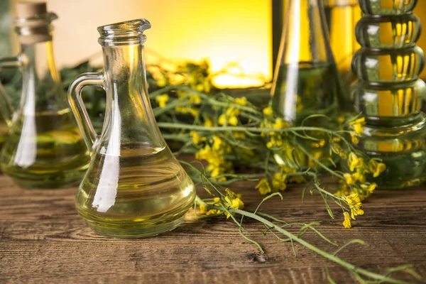 Rapeseed flowers and rapeseed oil in a bottle on the table