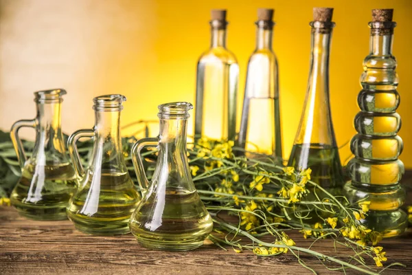 Koolzaadbloemen en raapzaadolie in een fles op tafel — Stockfoto