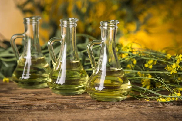 Rapeseed flowers and rapeseed oil in a bottle on the table — Stock Photo, Image