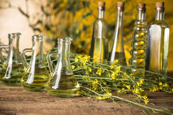 Rapeseed flowers and rapeseed oil in a bottle on the table