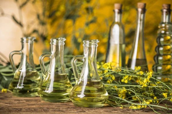Řepkové květy a řepkový olej v láhvi na stole — Stock fotografie