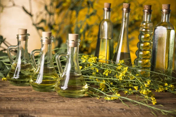 Fleurs de colza et huile de colza dans une bouteille sur la table — Photo