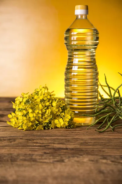 Rapeseed flowers and rapeseed oil in a bottle on the table — Stock Photo, Image