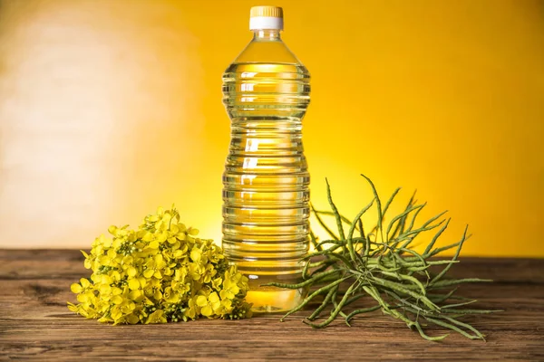 Rapeseed flowers and rapeseed oil in a bottle on the table