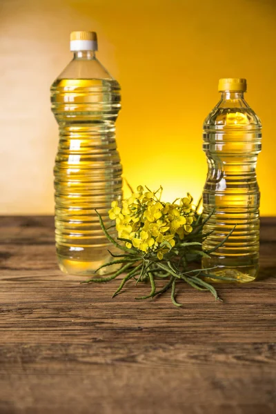 Rapeseed flowers and rapeseed oil in a bottle on the table