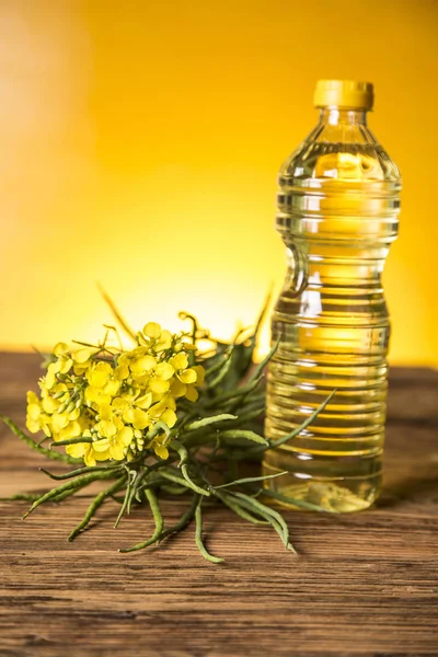 Rapeseed flowers and rapeseed oil in a bottle on the table — Stock Photo, Image