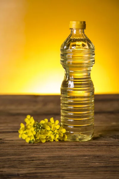 Rapeseed flowers and rapeseed oil in a bottle on the table