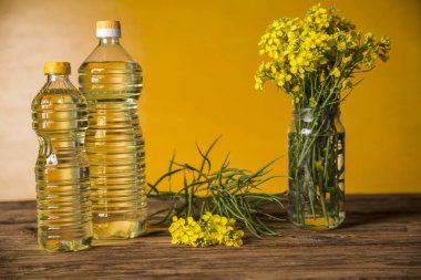 Rapeseed flowers and rapeseed oil in a bottle on the table clipart