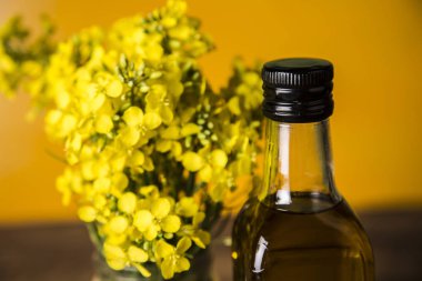 Masadaki şişede kolza tohumu çiçeği ve yağ var.
