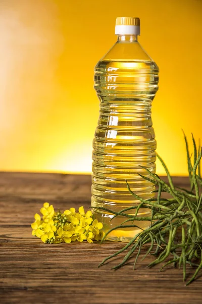 Kwiaty rzepaku i olej rzepakowy w butelce na stole — Zdjęcie stockowe