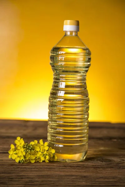 Rapeseed flowers and rapeseed oil in a bottle on the table