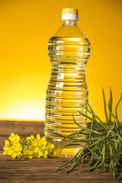 Rapeseed flowers and rapeseed oil in a bottle on the table