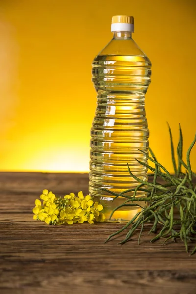 Rapeseed flowers and rapeseed oil in a bottle on the table