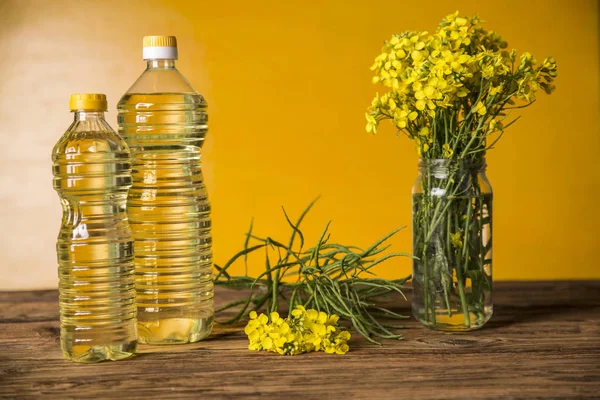 Квіти ріпаку та олія ріпаку в пляшці на столі — стокове фото