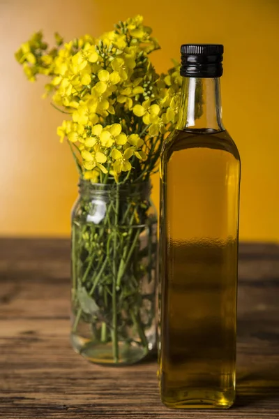 Рапсовые цветы и рапсовое масло в бутылке на столе — стоковое фото