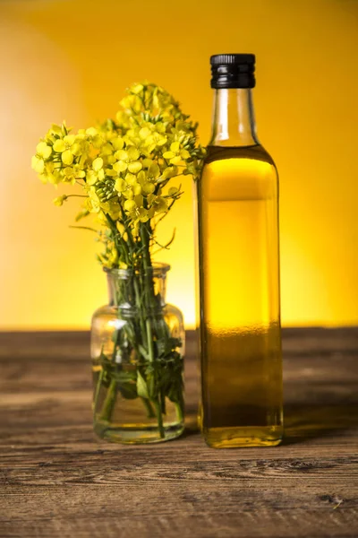 Fleurs de colza et huile de colza dans une bouteille sur la table — Photo