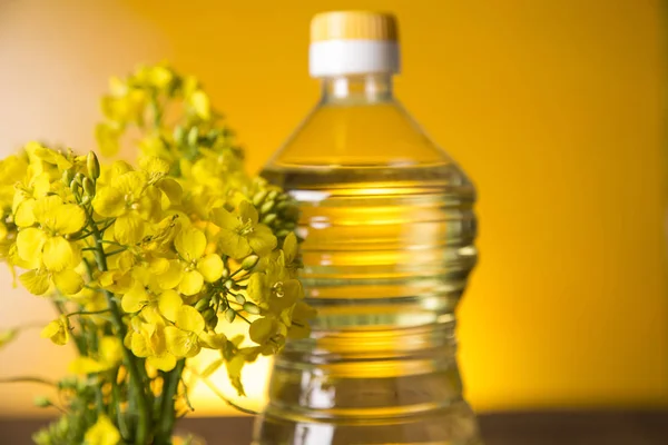 Rapeseed flowers and rapeseed oil in a bottle on the table