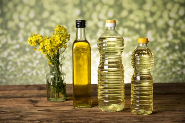 Rapeseed flowers and rapeseed oil in a bottle on the table — Stock Photo, Image