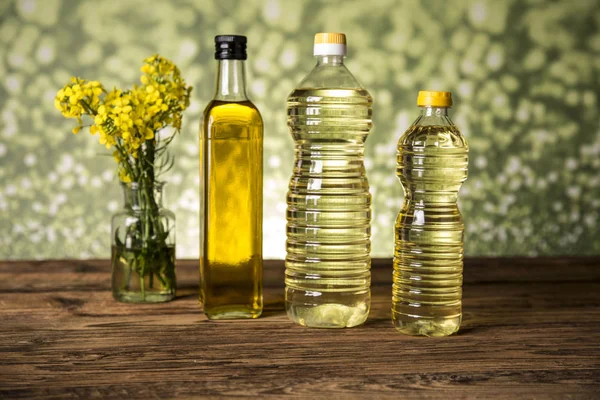 Fiori di colza e olio di colza in una bottiglia sul tavolo — Foto Stock