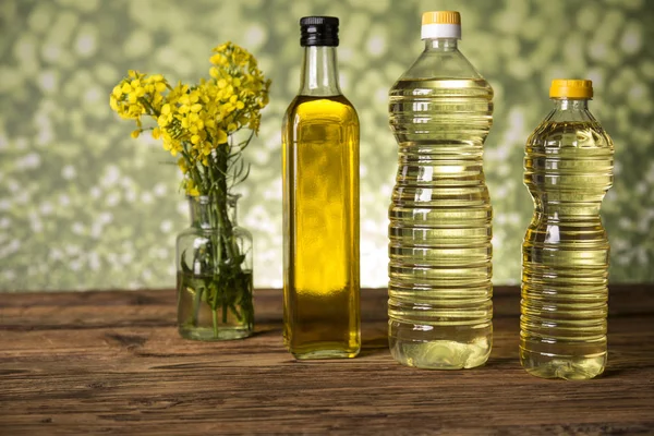 Flores de colza y aceite de colza en una botella sobre la mesa — Foto de Stock