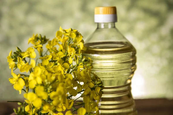 Rapeseed flowers and rapeseed oil in a bottle on the table