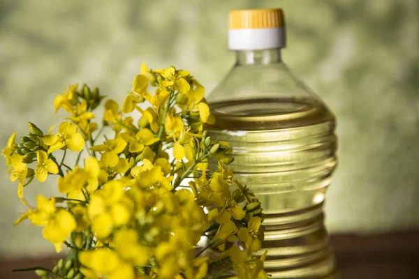 Rapeseed flowers and rapeseed oil in a bottle on the table