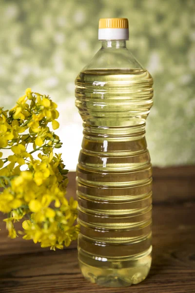 Рапсовые цветы и рапсовое масло в бутылке на столе — стоковое фото
