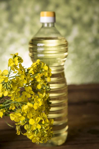 Flores de colza y aceite de colza en una botella sobre la mesa — Foto de Stock