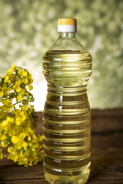 Rapeseed flowers and rapeseed oil in a bottle on the table