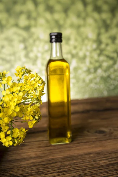 Flores de colza e óleo de colza em uma garrafa na mesa — Fotografia de Stock
