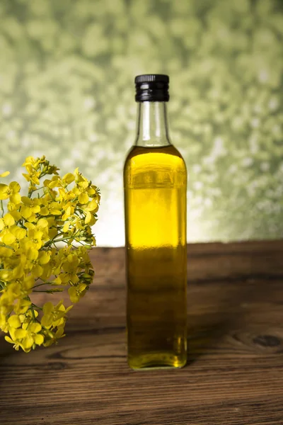Kwiaty rzepaku i olej rzepakowy w butelce na stole — Zdjęcie stockowe