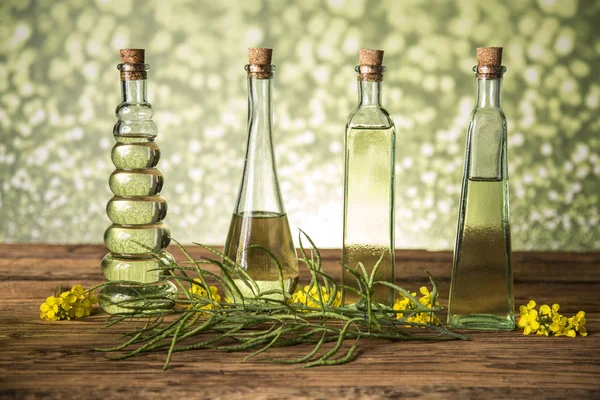 Seeds and rape flowers in bottles and carafes with rapeseed oil — Stock Photo, Image