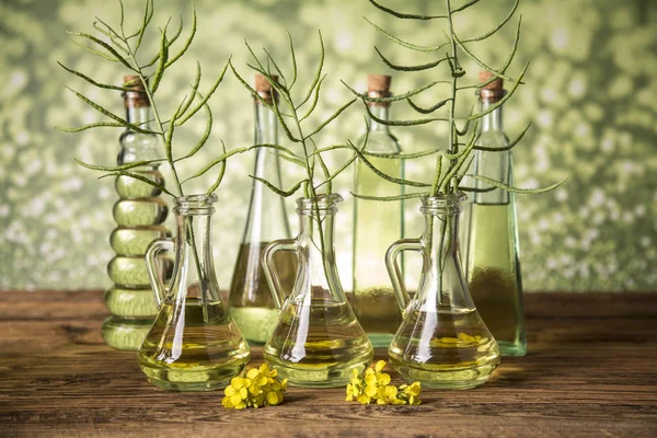 Seeds and rape flowers in bottles and carafes with rapeseed oil — Stock Photo, Image