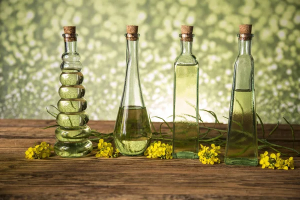 Semillas y flores de colza en botellas y jarras con aceite de colza — Foto de Stock