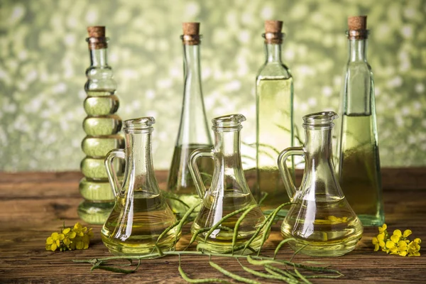 Seeds and rape flowers in bottles and carafes with rapeseed oil — Stock Photo, Image