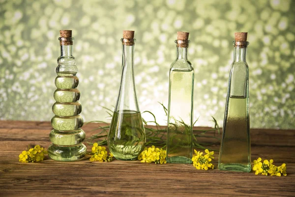 Seeds and rape flowers in bottles and carafes with rapeseed oil — Stock Photo, Image