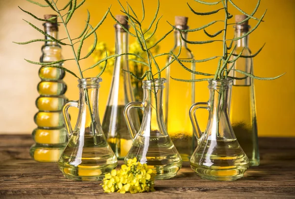 Seeds and rape flowers in bottles and carafes with rapeseed oil — Stock Photo, Image