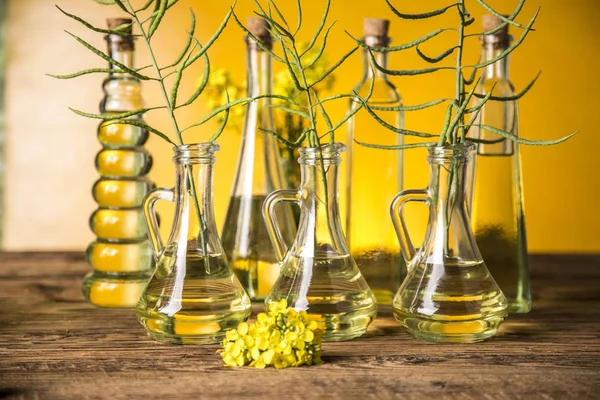 Zaden en verkrachting bloemen in flessen en karaffen met raapzaad olie — Stockfoto